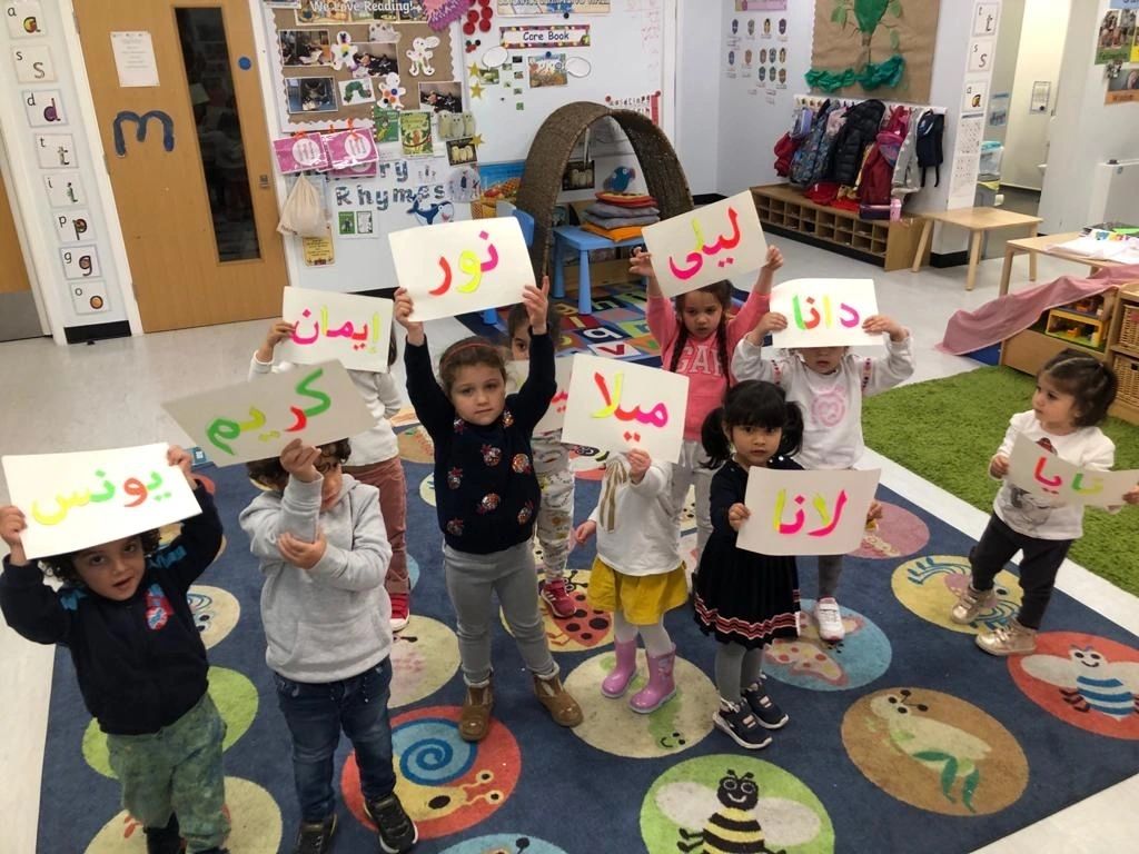 Children holding Arabic letter cards in classroom