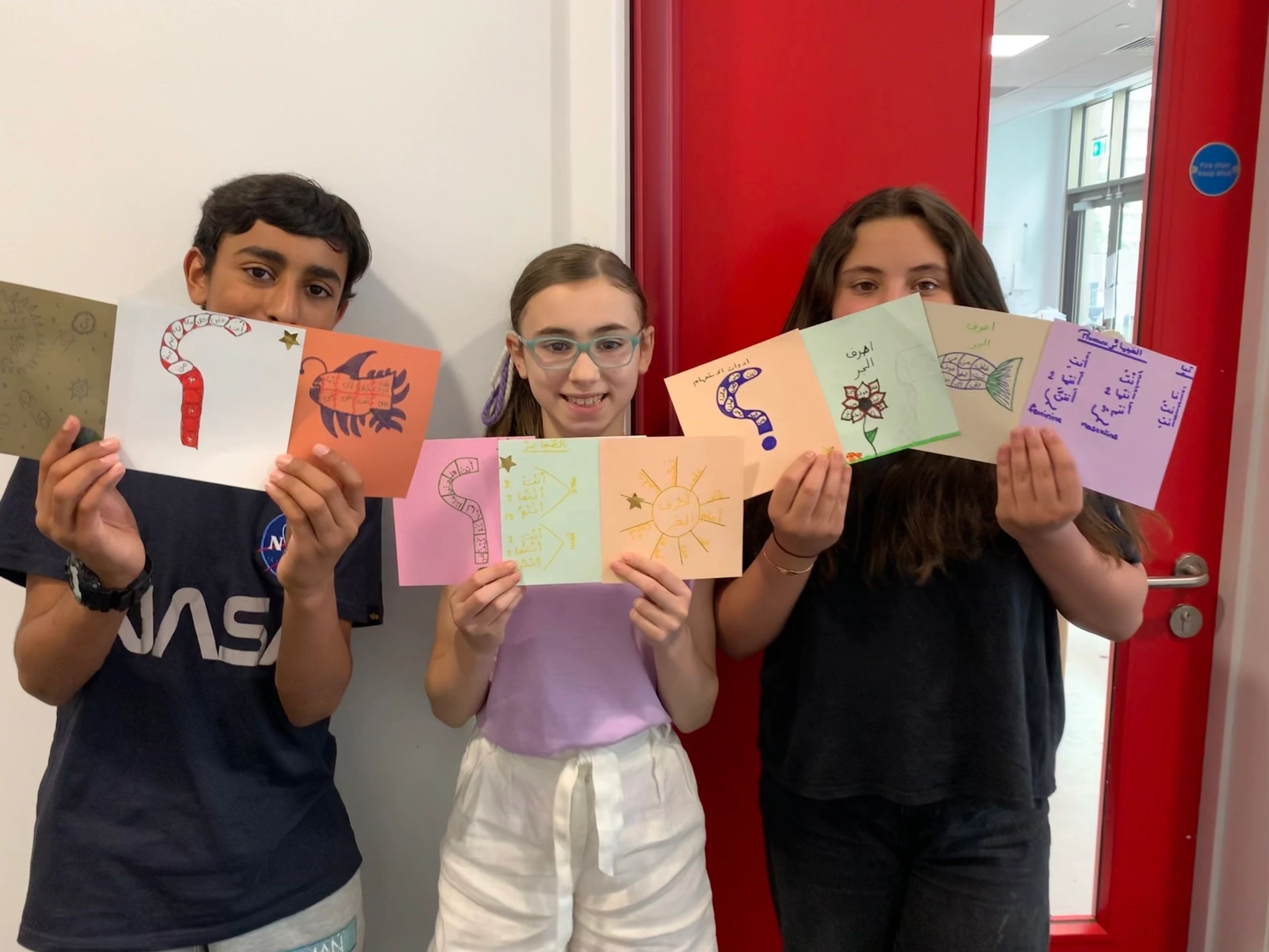 Children displaying Arabic artwork cards